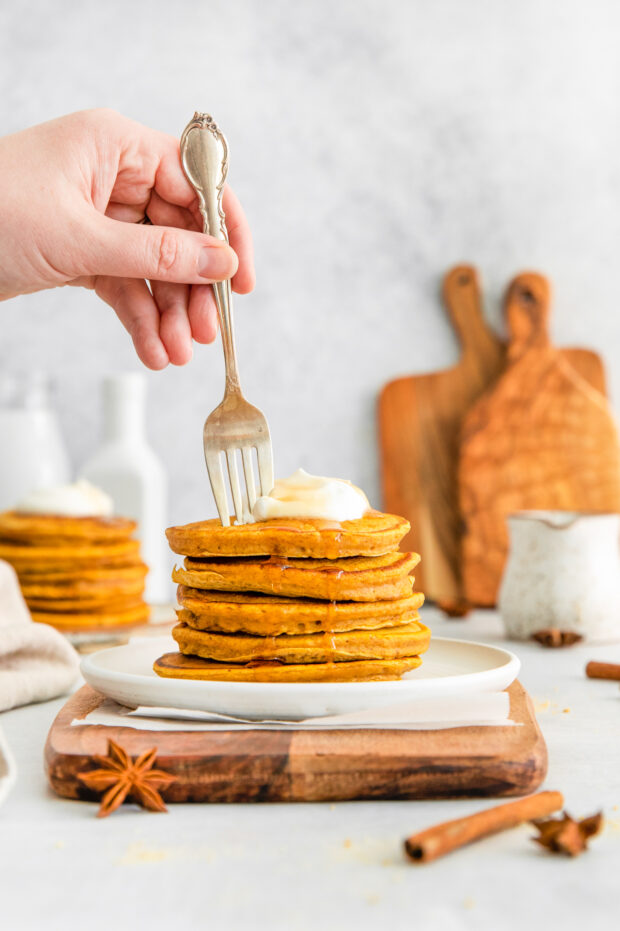 A fork going into a stack of pumpkin pancakes. 