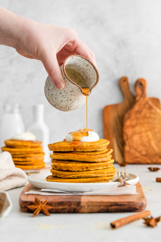 maple syrup getting poured over pumpkin pancakes. 