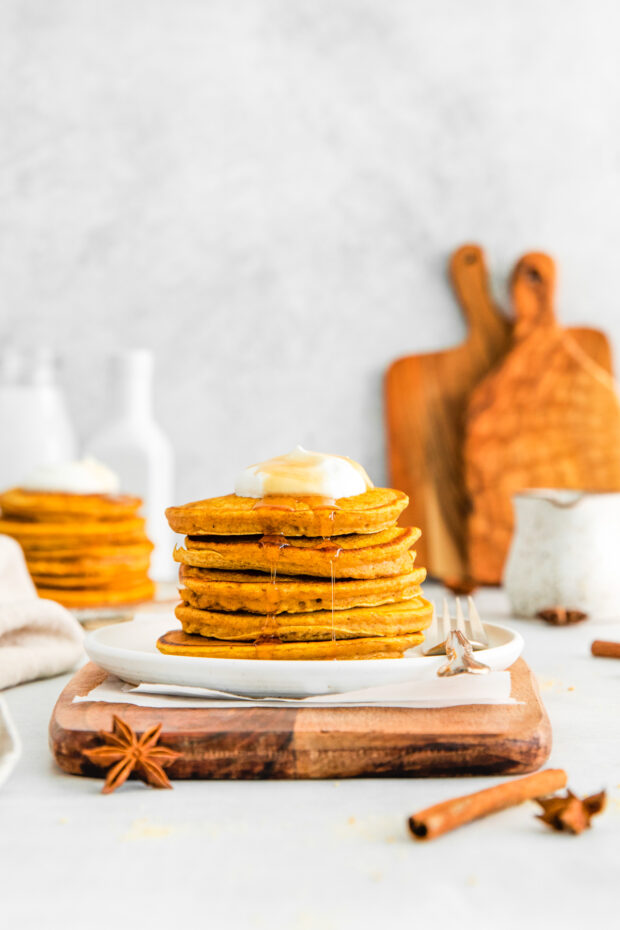 Maple syrup dripping over the edge of a stack of pancakes. 