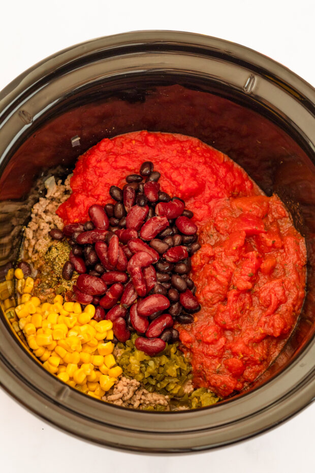 Ingredients for taco chili in the slow cooker bowl. 