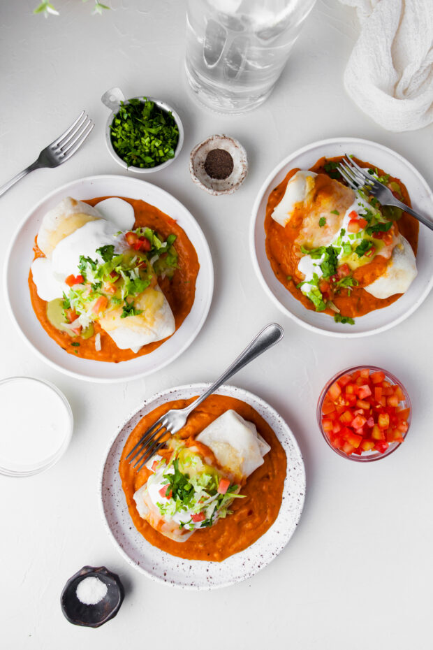 Smothered Burritos on a plate with extra sauce. 