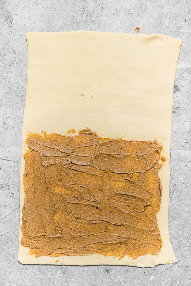 Cinnamon sugar butter spread out on puff pastry. 