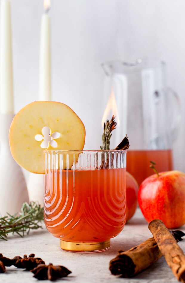 Instant Pot Apple Cider in a glass garnished with flaming rosemary. 