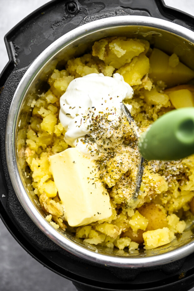 Potatoes getting mashed with butter, sour cream and spices.