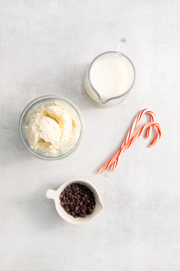 Ice cream, milk, candy canes, and chocolate chips sitting on a table.