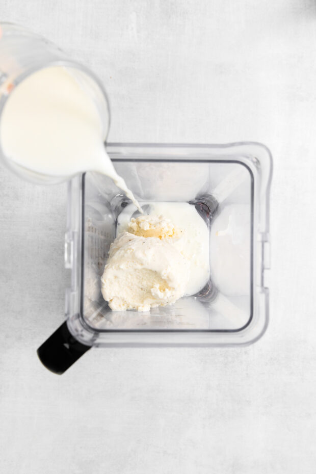 Pouring milk into ice cream in a blender.