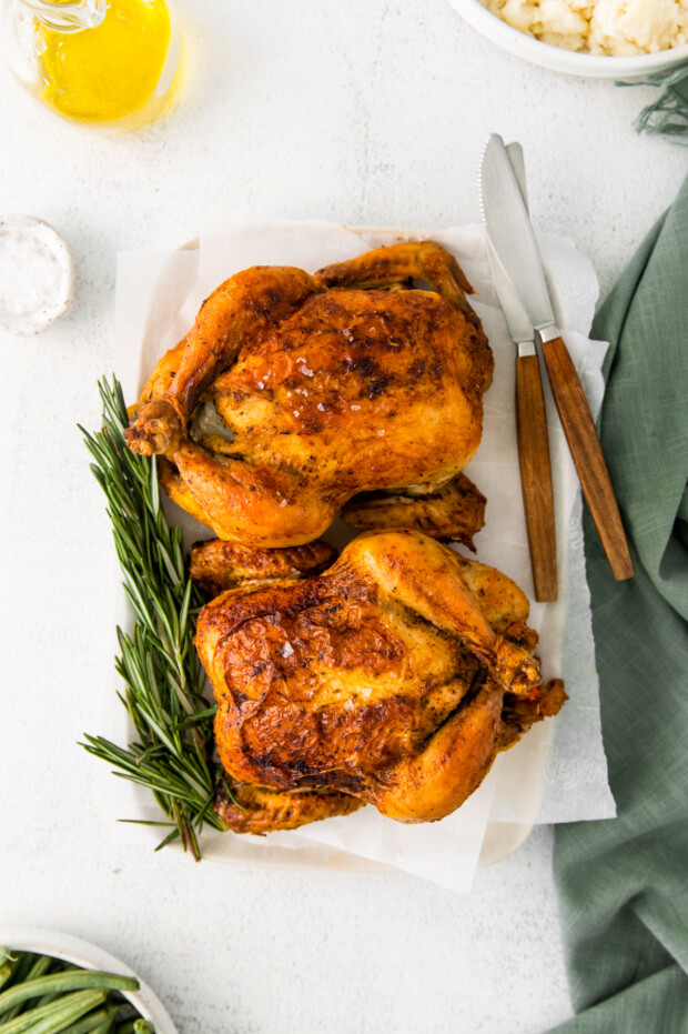 Roasted Cornish Hens on a serving platter with fresh herbs. 