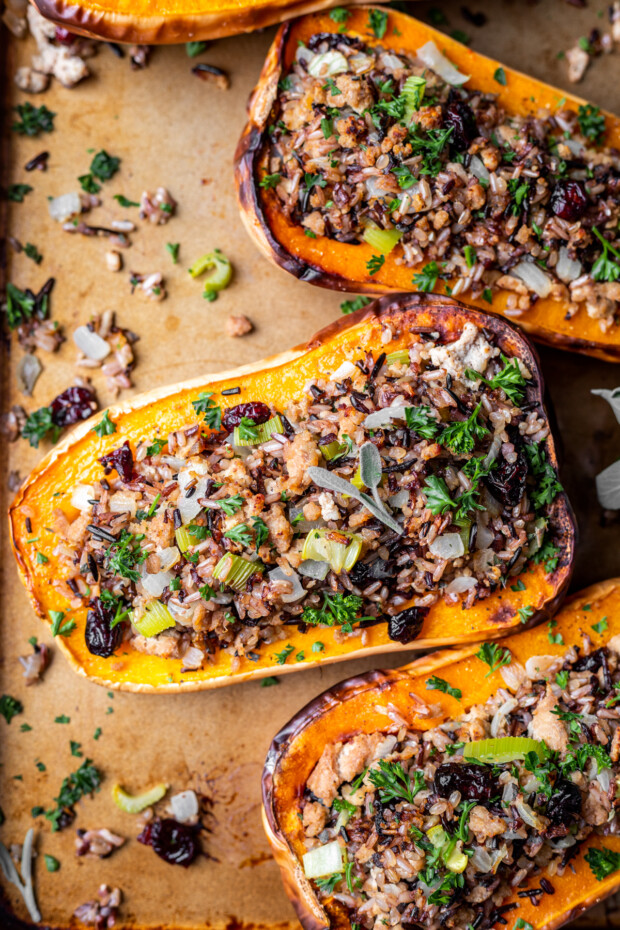 Stuffed Butternut Squash on a sheet pan with fresh herbs. 