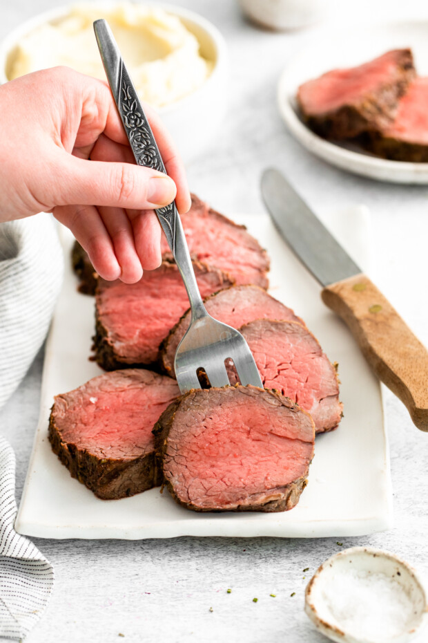 A fork picking up a slice of Air Fryer Beef Tenderloin. 