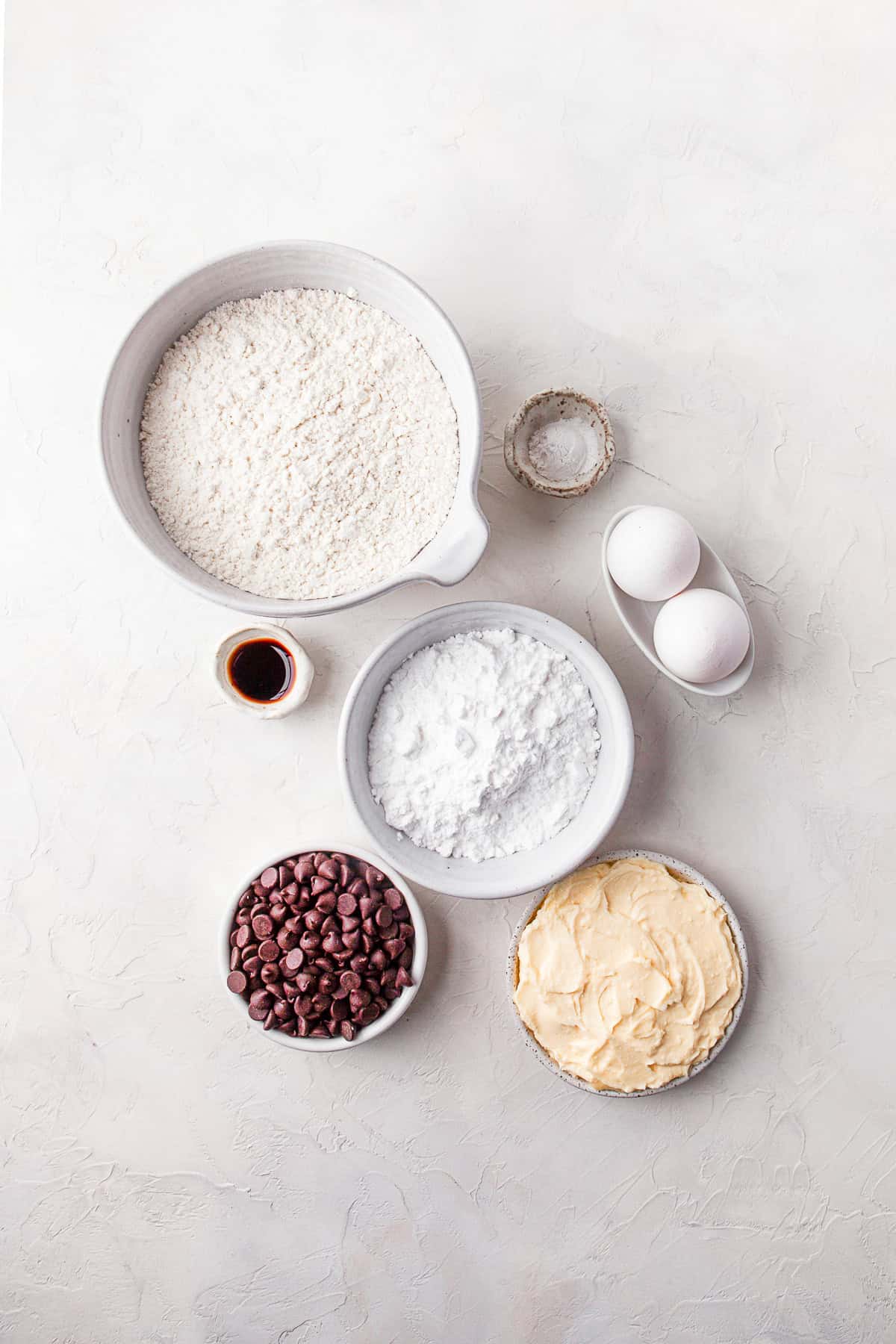 Butter, powdered sugar, chocolate chips, eggs, and vanilla extract on a table. 