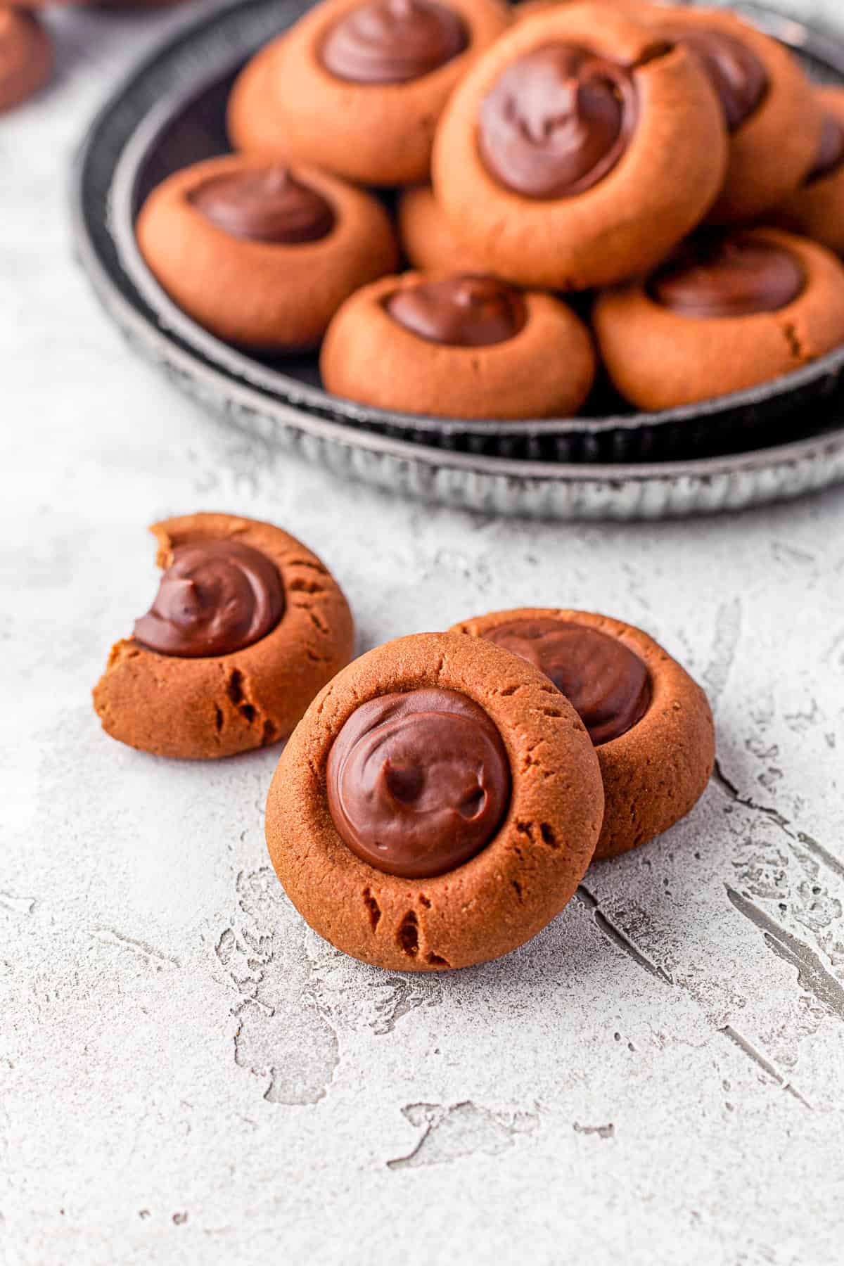 Double Chocolate Thumbprint Cookies sitting on a table with more cookies in the back.
