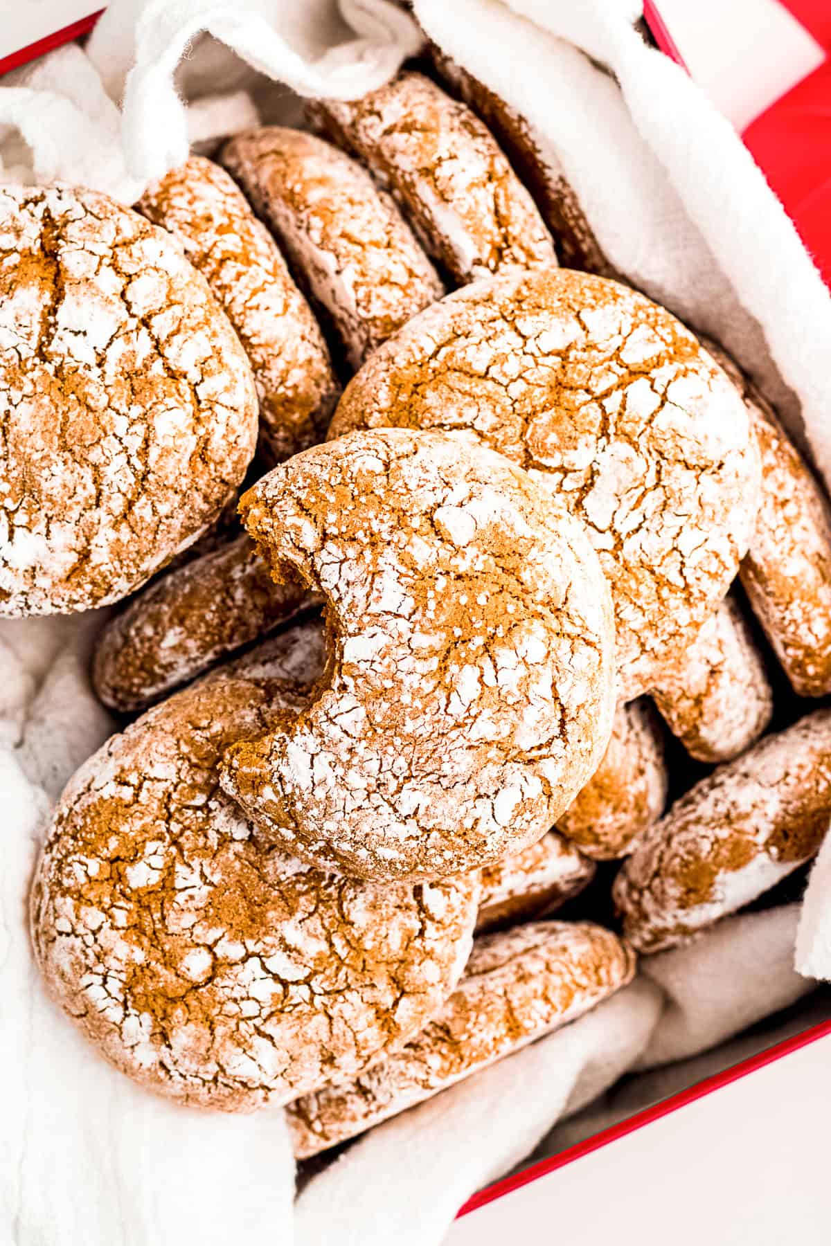 Molasses Crinkle Cookies in a box with a bite take out of one cookie.