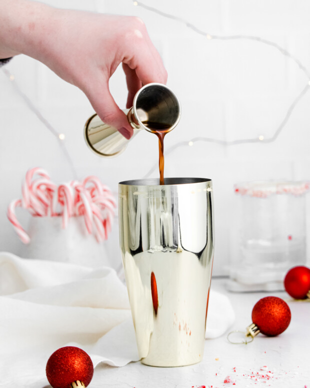 Pouring kahlua into a cocktail shaker. 