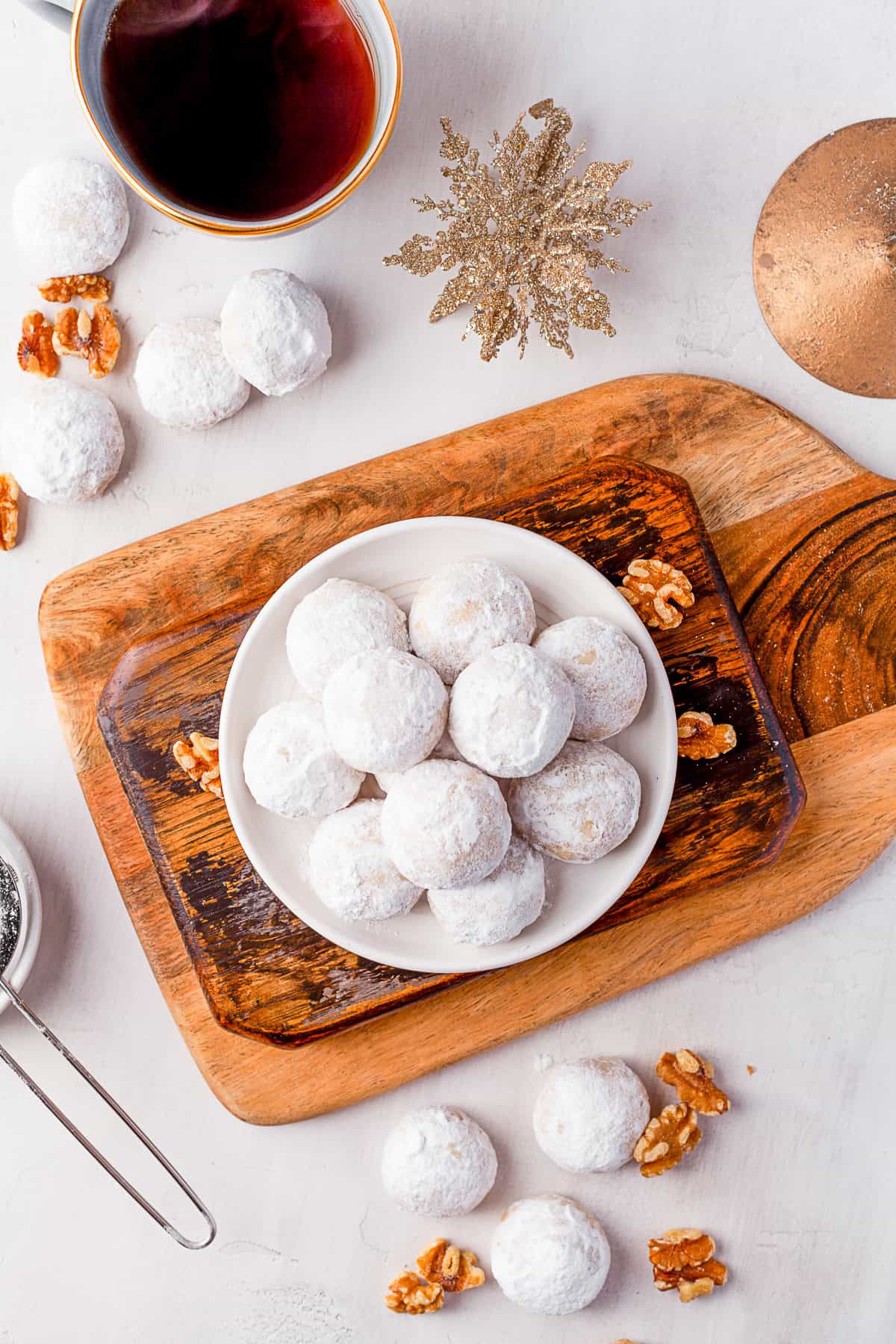 Snowball Cookies on a white plate sitting on wooden cutting boards. 