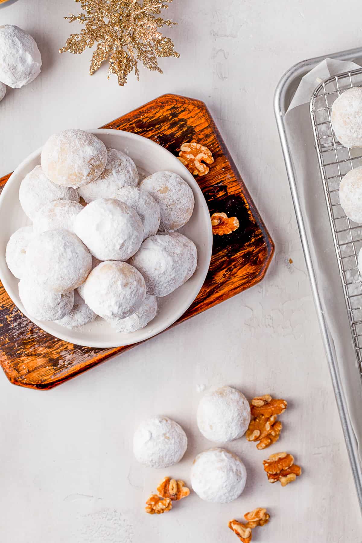 Snowball Cookies on a small white plate on a wooden cutting board. 