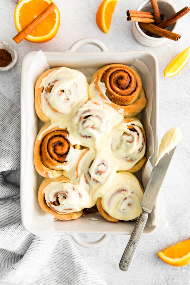 Spiced Orange Cinnamon Rolls in a dish topped with frosting.