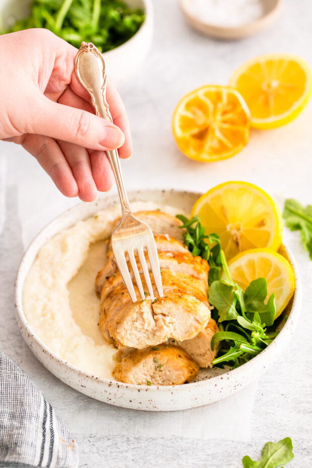 A fork picking up a slice of Air Fryer Lemon Chicken. 