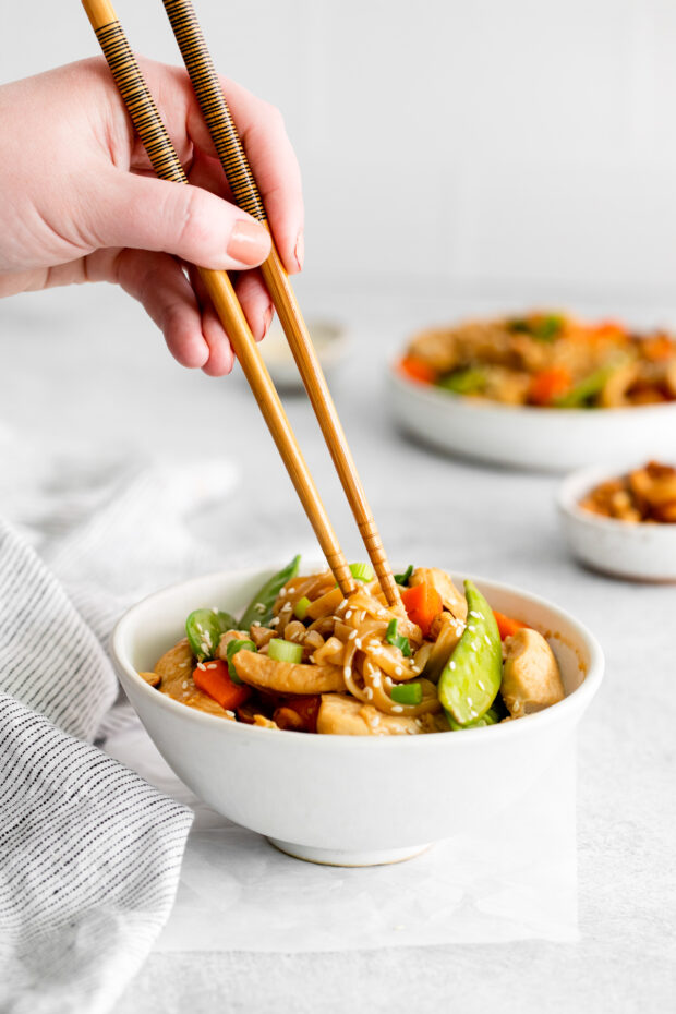 Cashew Chicken Pad Thai with a hand holding chopsticks picking up the noodles. 