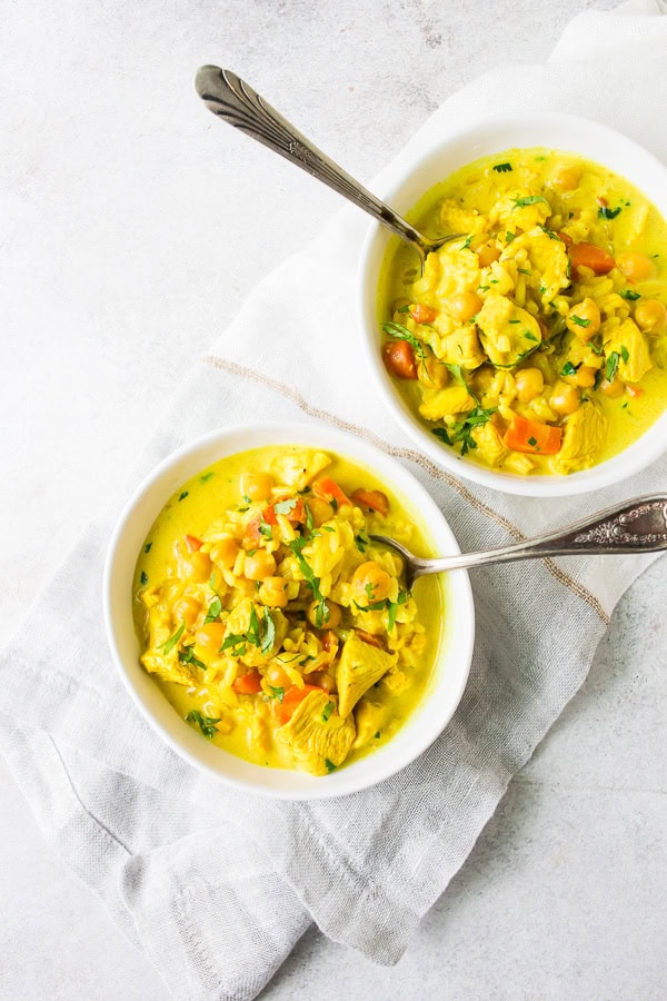 Chicken Coconut Milk Turmeric Soup in 2 small white bowls with spoons. 