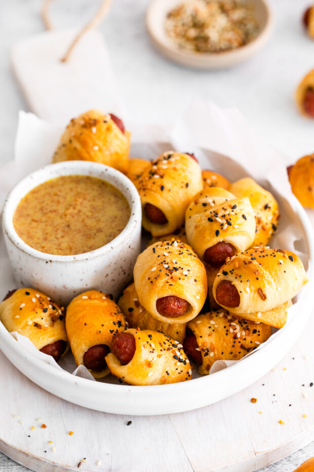 Everything Bagel Pigs in a Blanket in a bowl with dipping sauce.