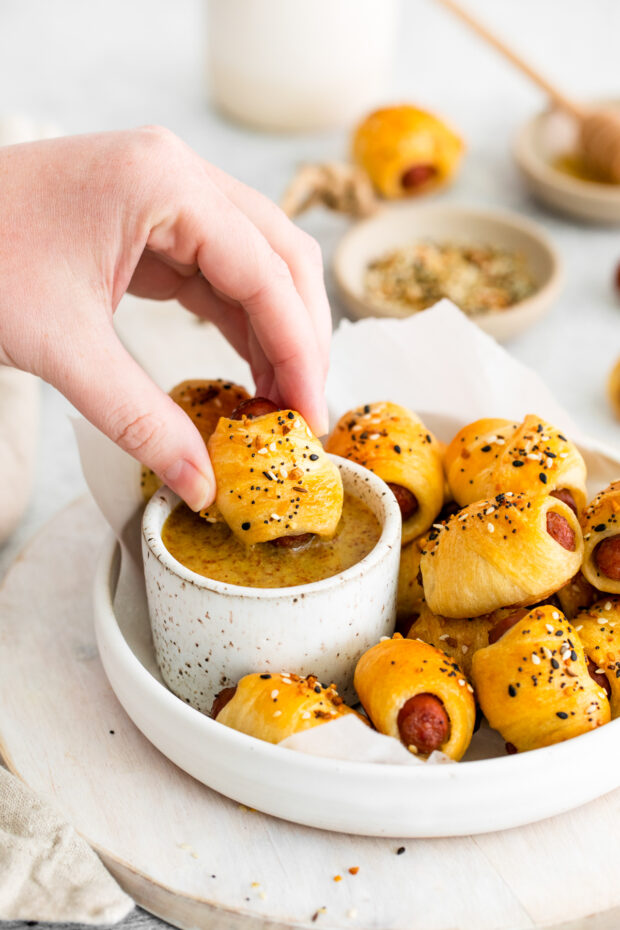 Dipping a Everything Bagel Pigs in a Blanket into homemade sauce.