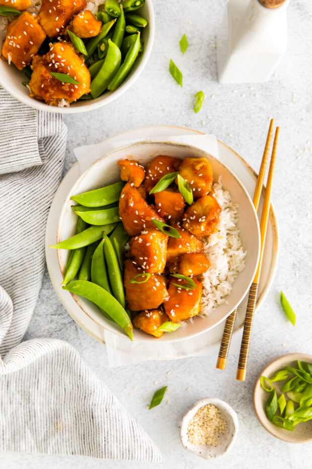 Honey Garlic Chicken Bowls served in a bowl with chopsticks and green onion.