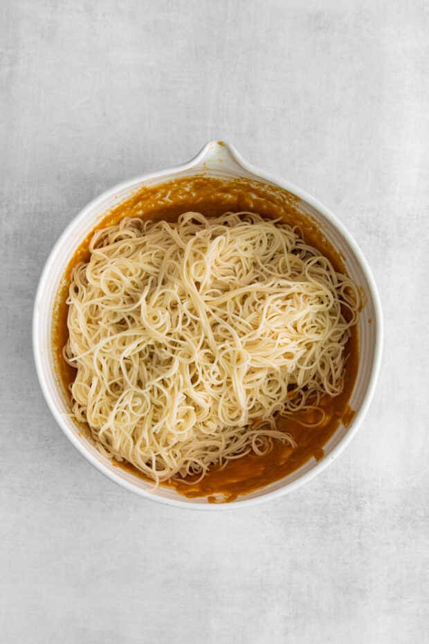 Noodles in a bowl with spicy peanut sauce.