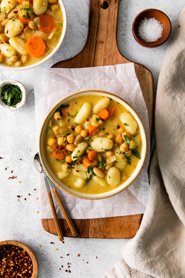 Vegetable Gnocchi Soup in a bowl sitting on a cutting board.