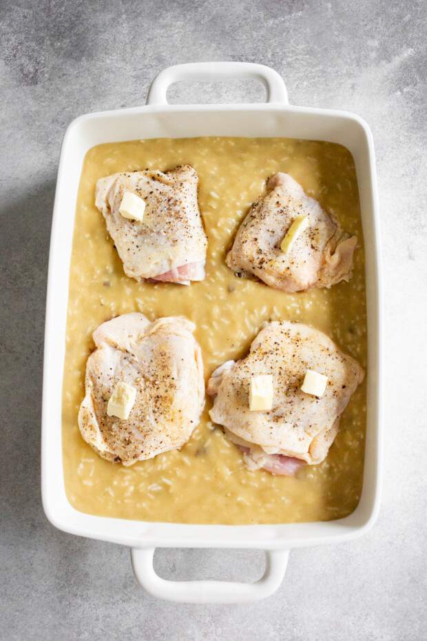 Uncooked creamy rice with chicken in a dish.