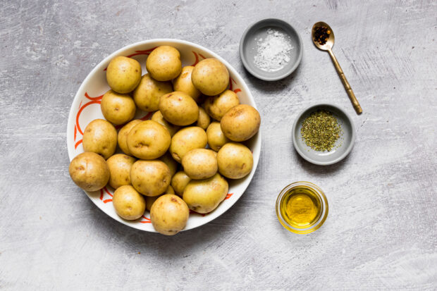 Potatoes, spices, and oil sitting on a table.