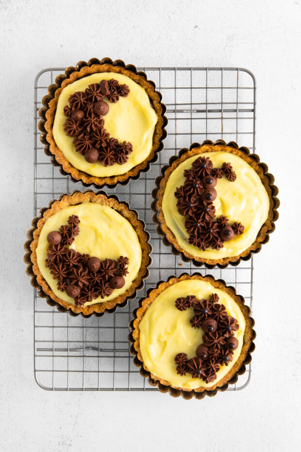 Boston Cream Pie Tarts cooling on a rack.