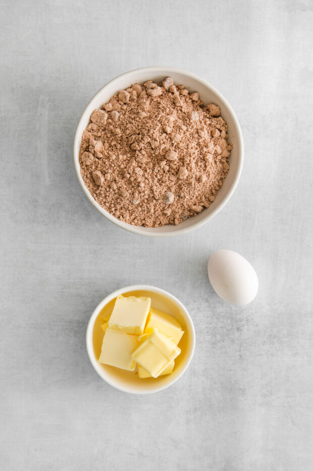 Brownie mix, egg, and butter sitting on a table. 