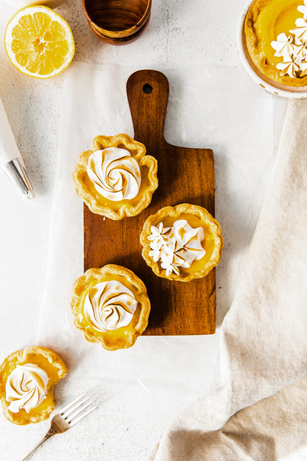 Mini Lemon Meringue Tarts on a cutting board. 