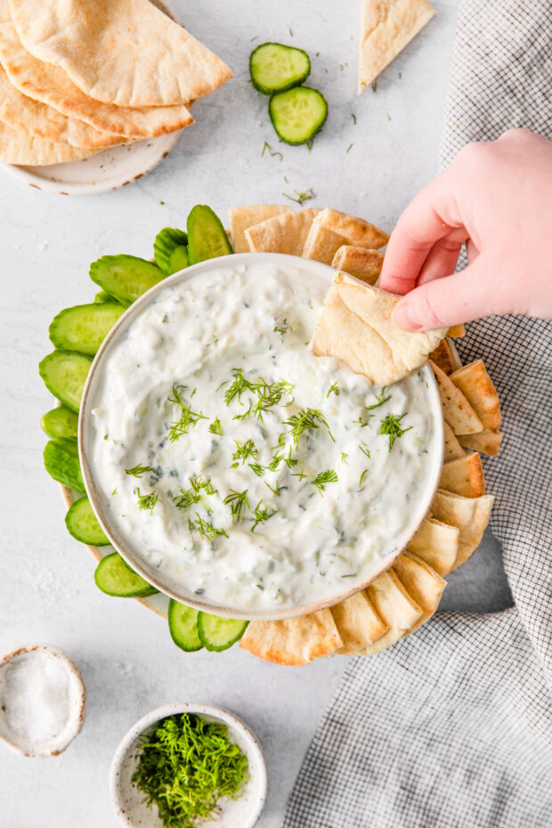 Tzatziki Sauce being scooped up with pita bread.