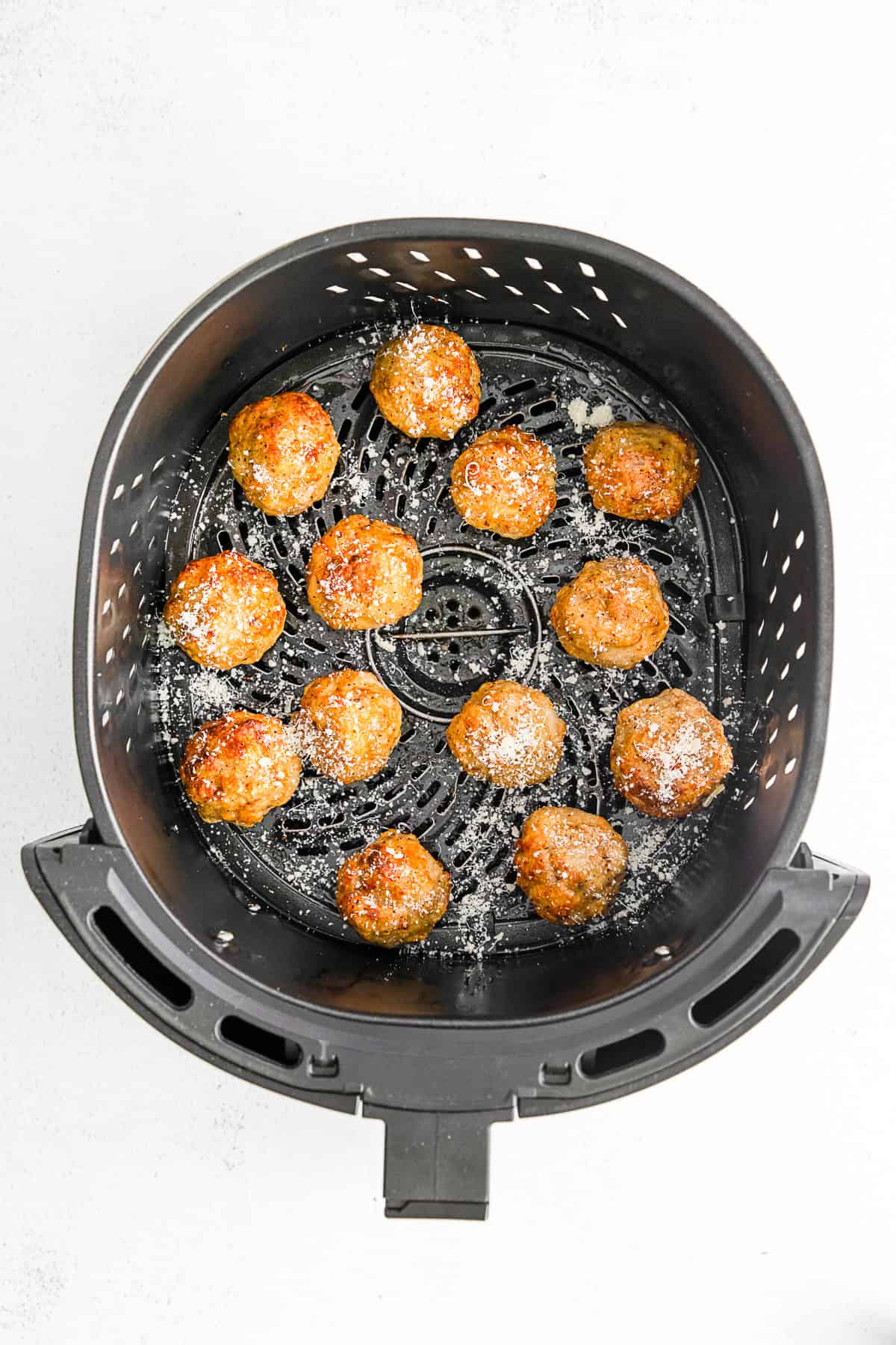 Cooked chicken meatballs in an air fryer basket. 