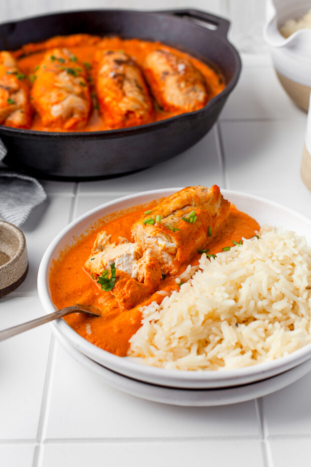 Stuffed chicken cut in half to show the cream cheese middle served with rice. 