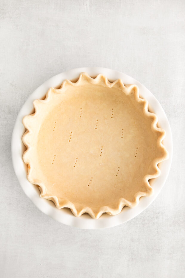 A pie crust with a few fork holes in the bottom of the dough.