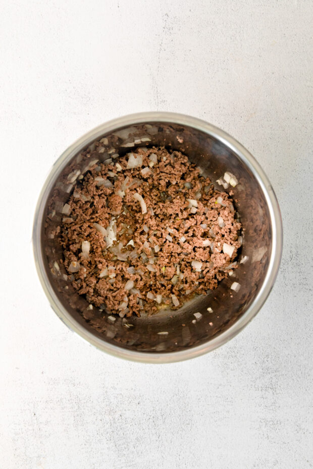 Ground beef and onion in the Instant Pot bowl.