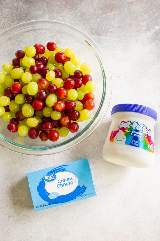 Grapes, cream cheese, and marshmallow creme on a table. 