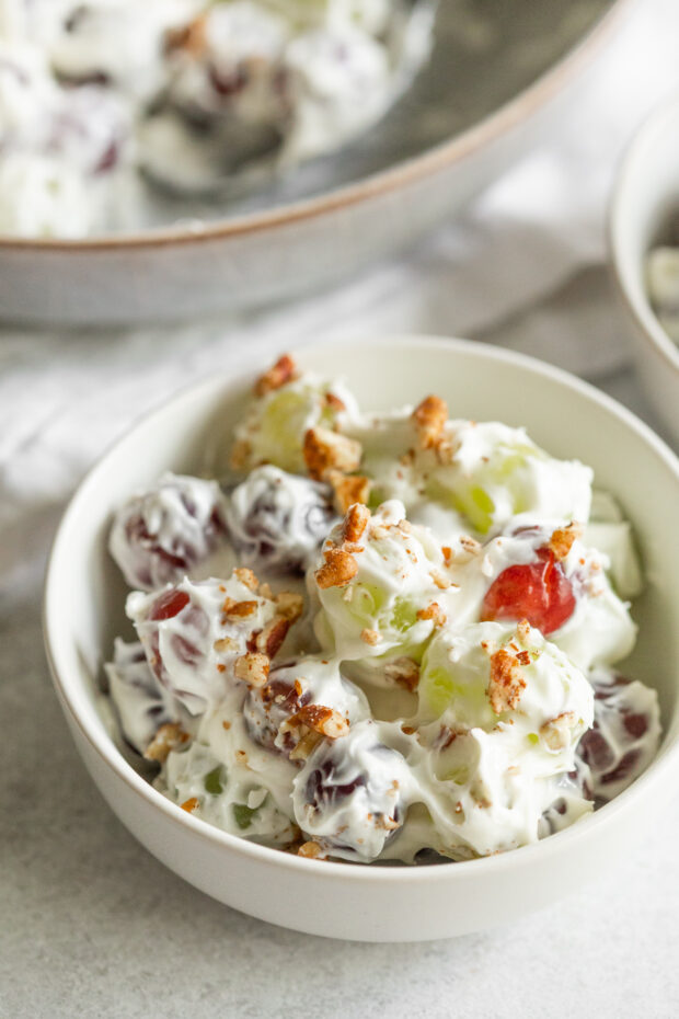 Creamy and sweet grape salad in a bowl topped with chopped pecans. 