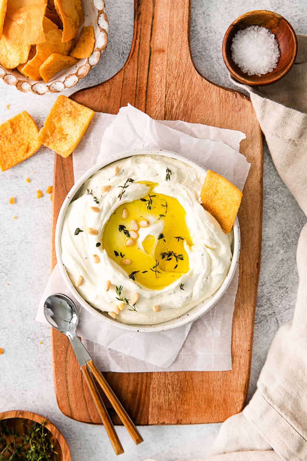 Roasted Garlic Whipped Feta garnished with pita chips and herbs.