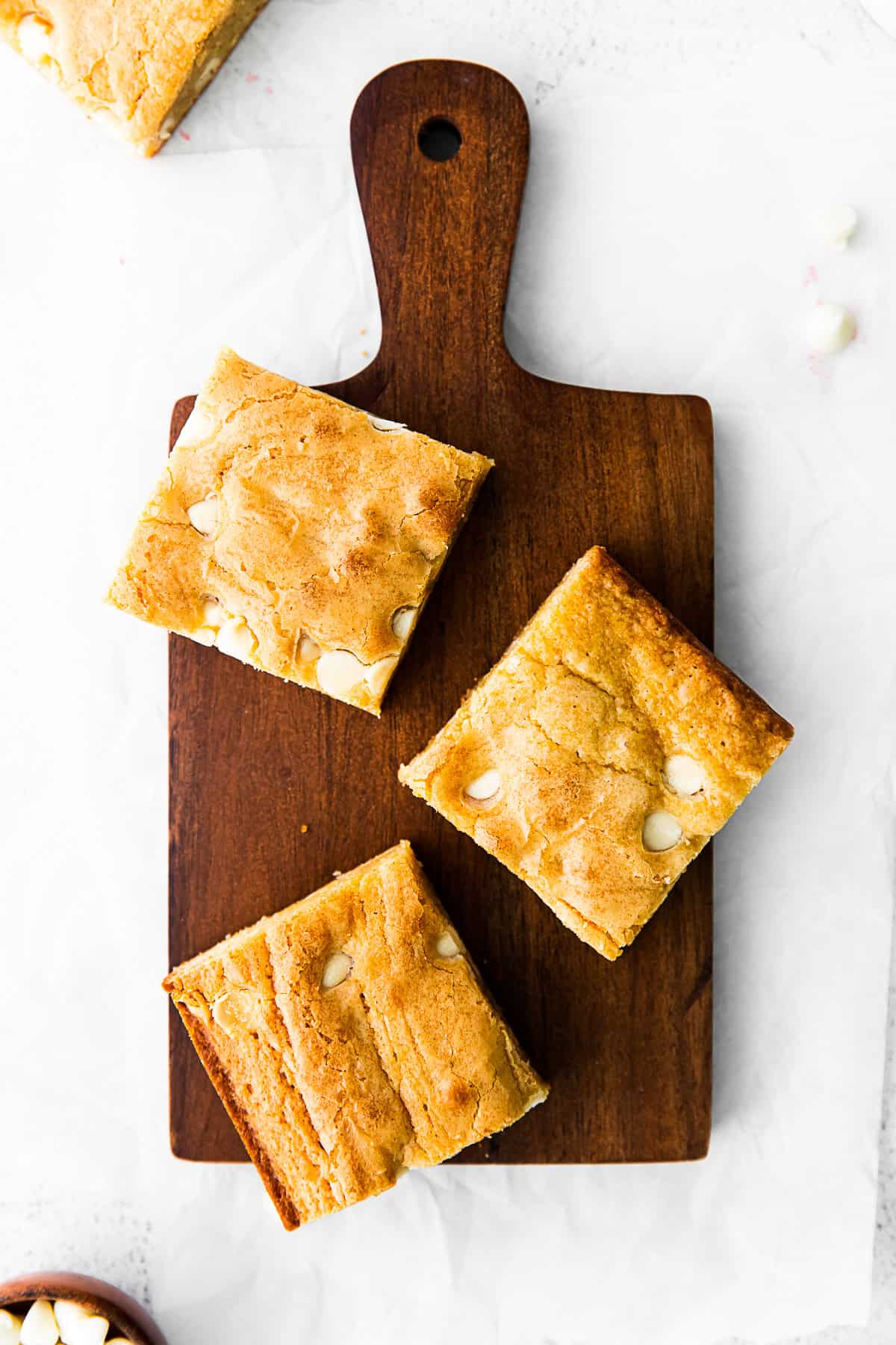 Cut White Chocolate Chip Blondies on a board. 