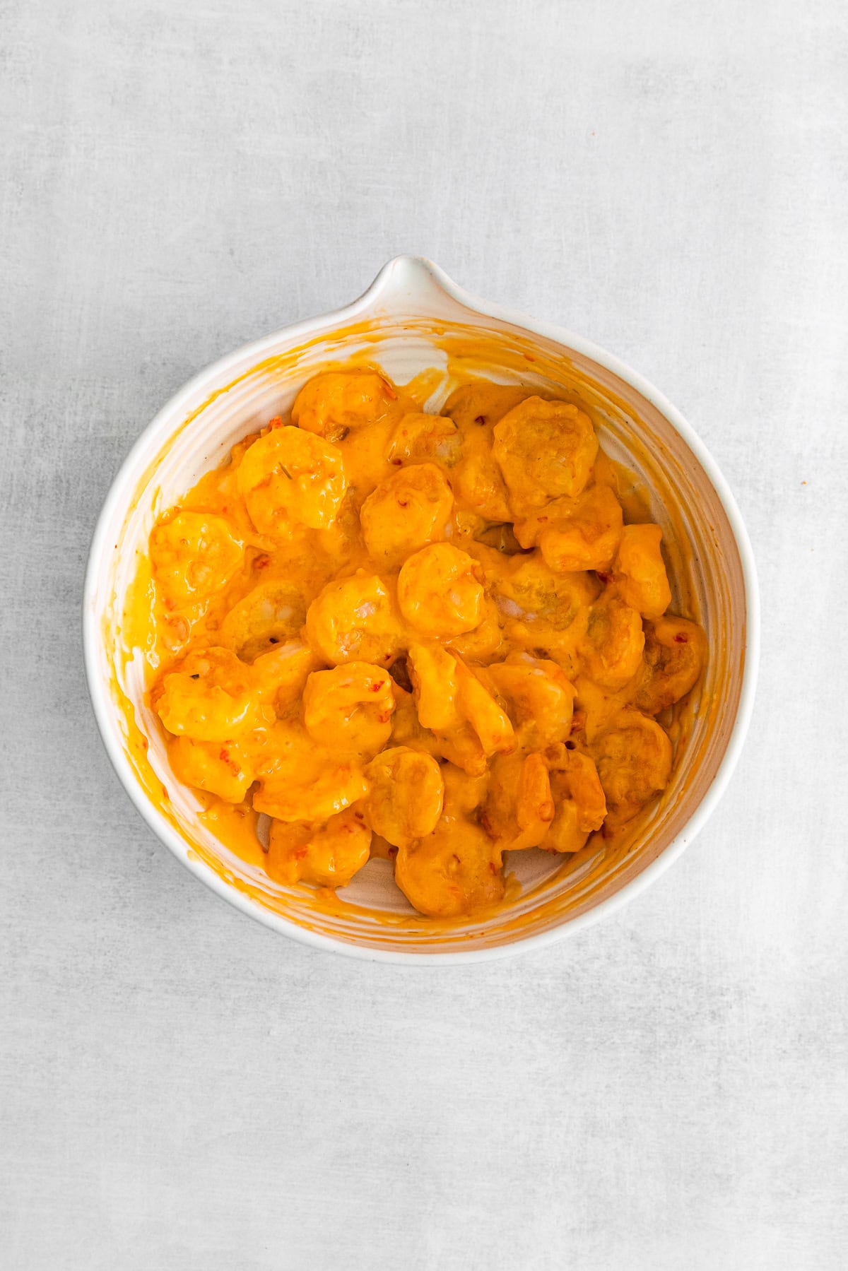 Fried shrimp tossed in bang bang sauce in a bowl.