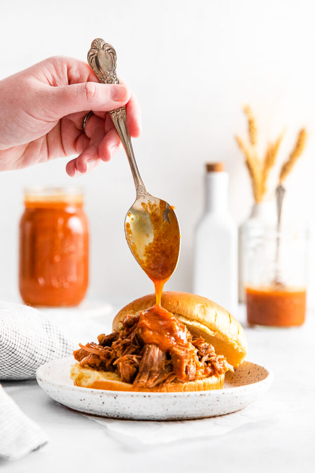 Drizzling bbq sauce over pulled pork.