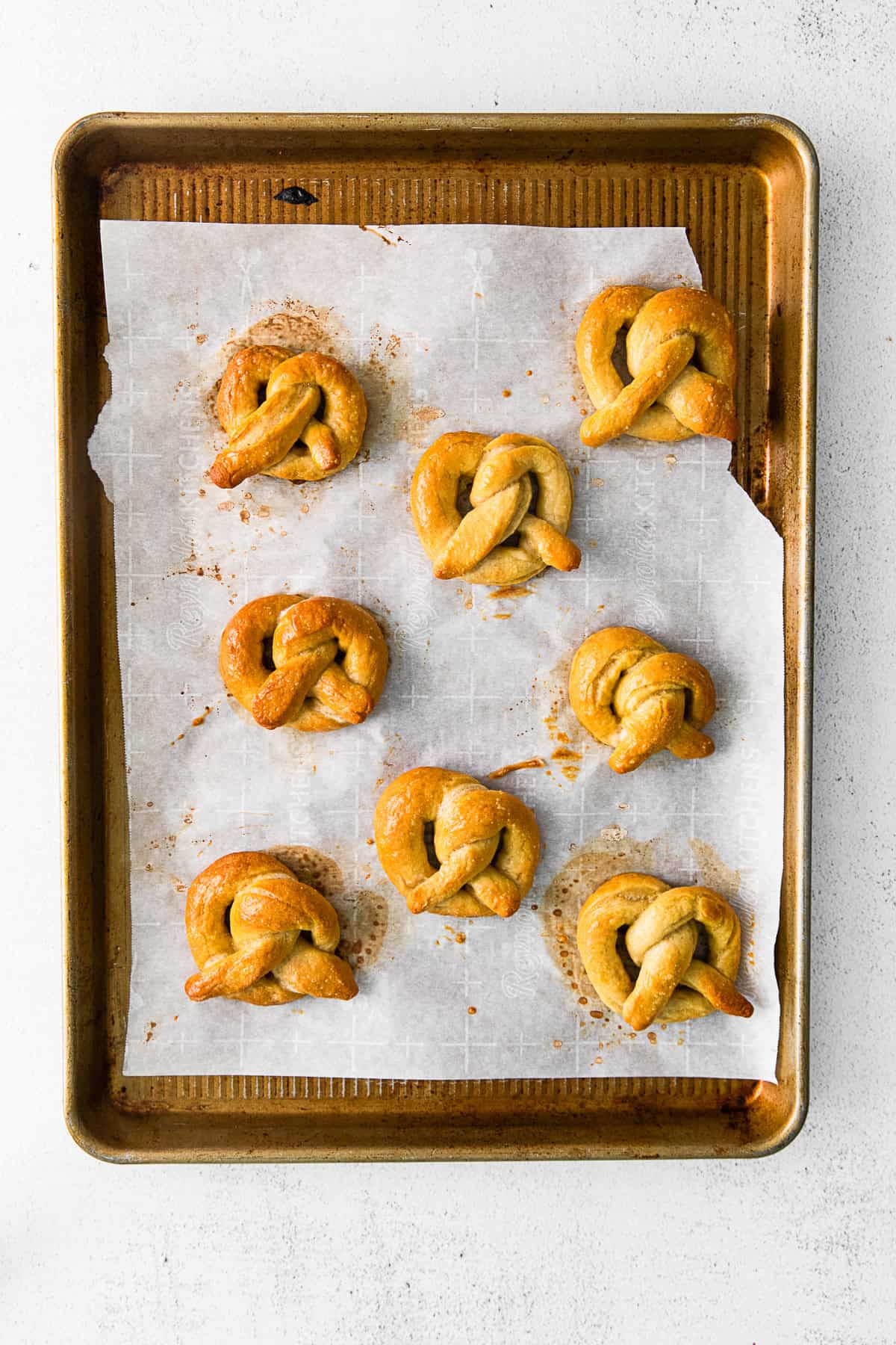 Cooked soft pretzels on a baking tray.