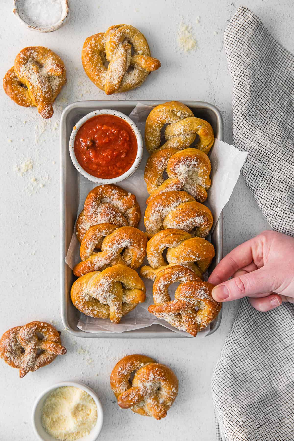 A hand grabbing a Garlic Parmesan Soft Pretzel.