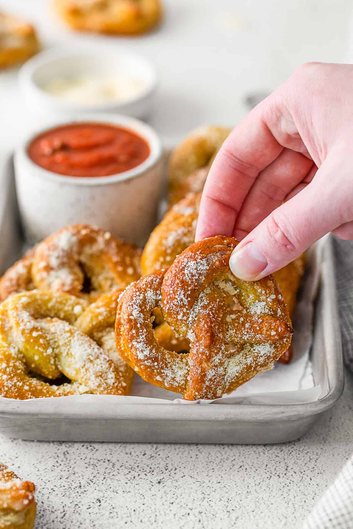 A hand holding Garlic Parmesan Soft Pretzels.