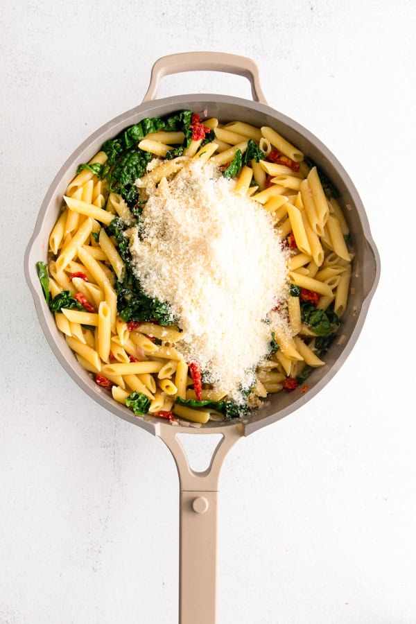 Pasta in a pan with Parmesan cheese.