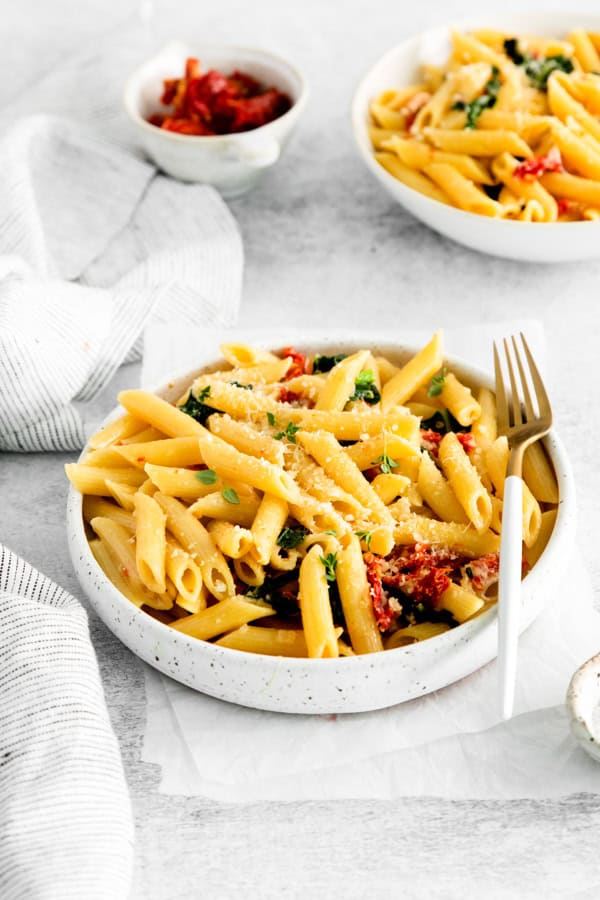 Sun dried Tomato and Kale Pasta in a white bowl with a fork.