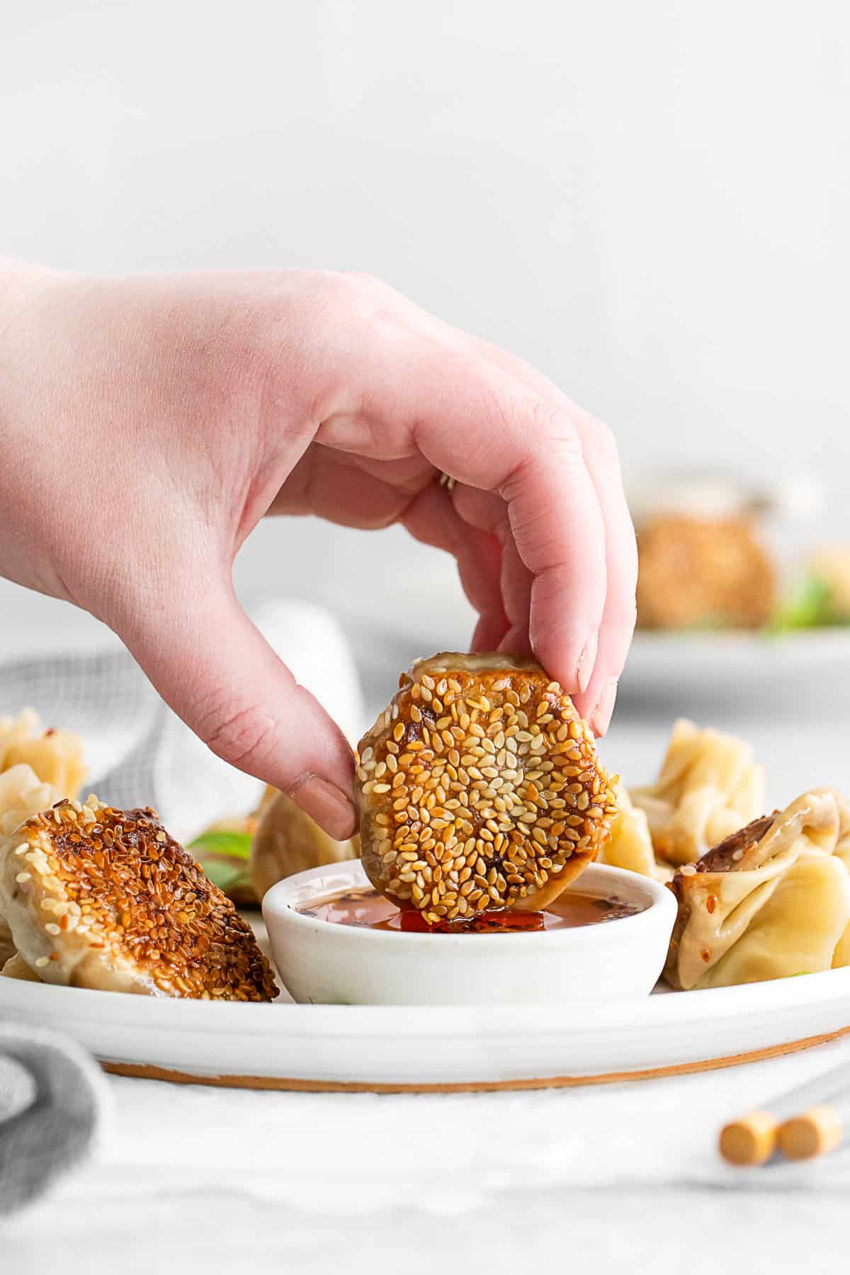 A hand dipping Shiitake Mushroom Dumplings into chili garlic oil. 